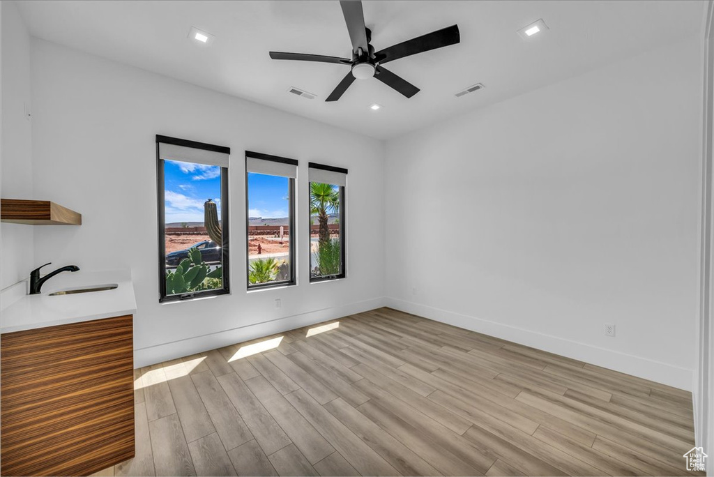 Unfurnished room featuring light wood-type flooring, a ceiling fan, a sink, baseboards, and recessed lighting