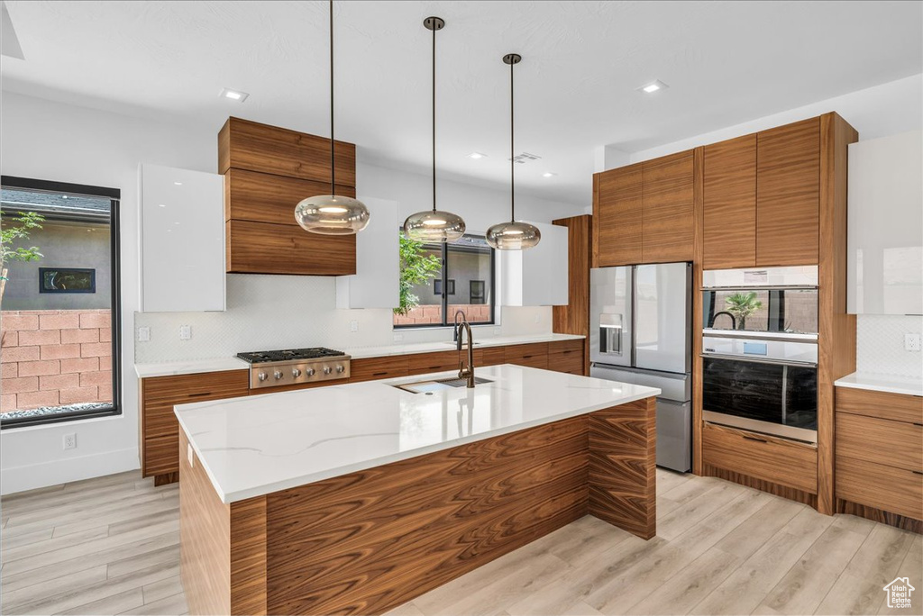 Kitchen featuring stainless steel appliances, brown cabinets, a sink, modern cabinets, and recessed lighting