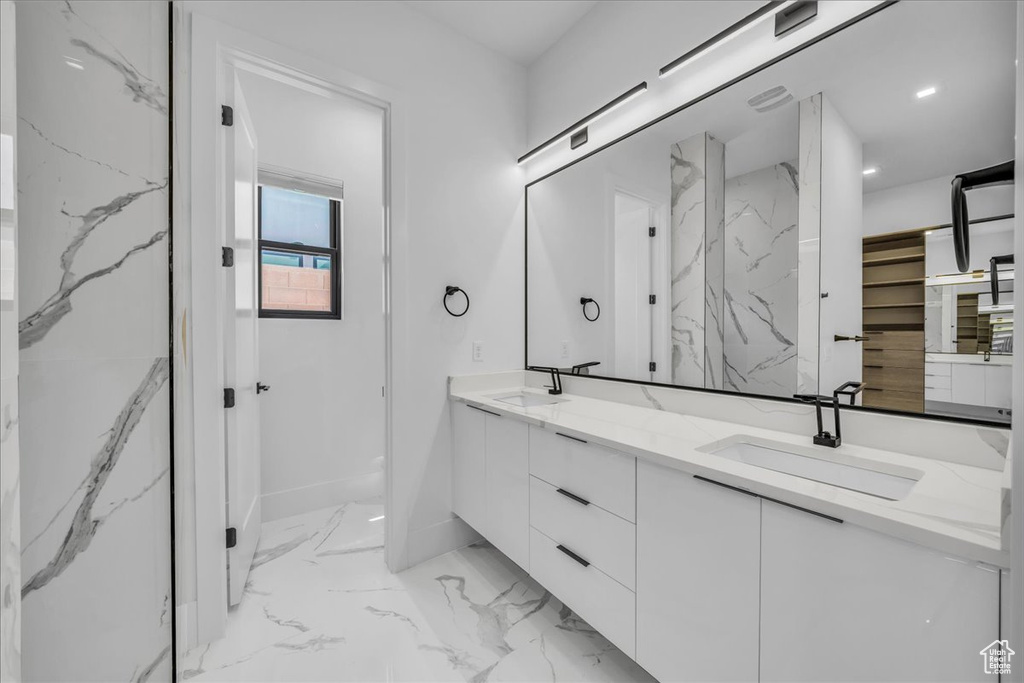 Full bathroom featuring double vanity, marble finish floors, and a marble finish shower