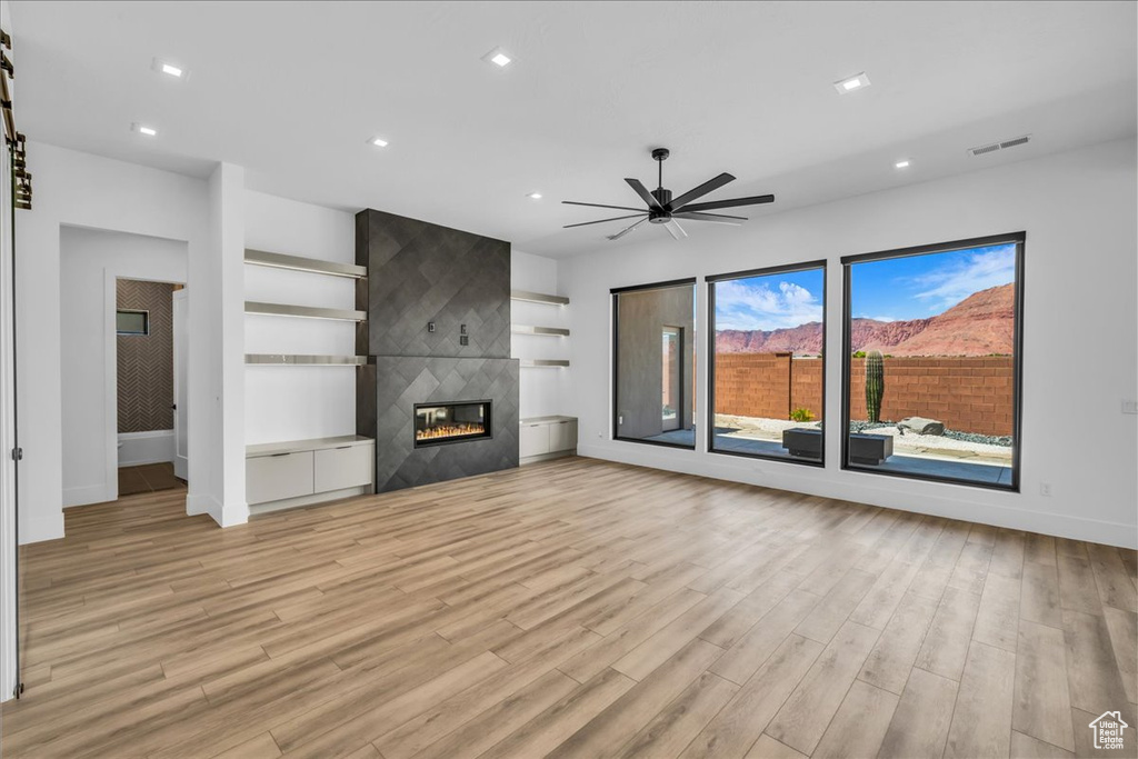 Unfurnished living room with light wood finished floors, baseboards, ceiling fan, and recessed lighting