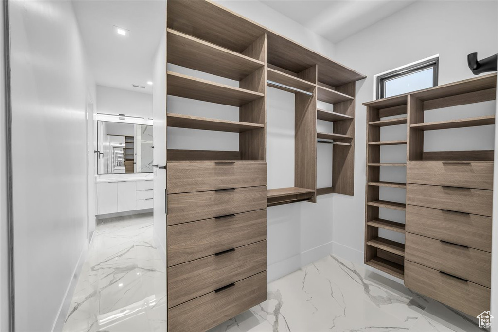 Spacious closet featuring light marble finish floors