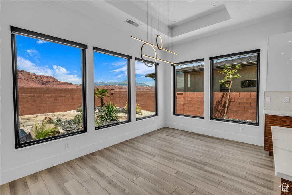 Unfurnished sunroom with plenty of natural light, a tray ceiling, and wood finished floors