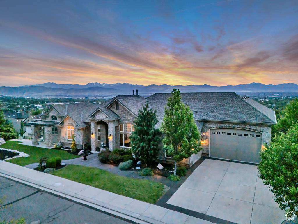 French country style house featuring stone siding, a mountain view, driveway, and an attached garage