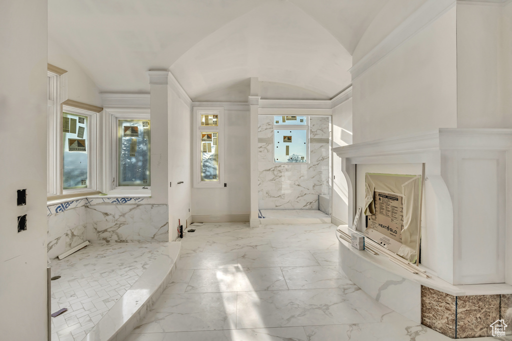 Full bathroom with lofted ceiling, marble tiled flooring, and a marble finish shower