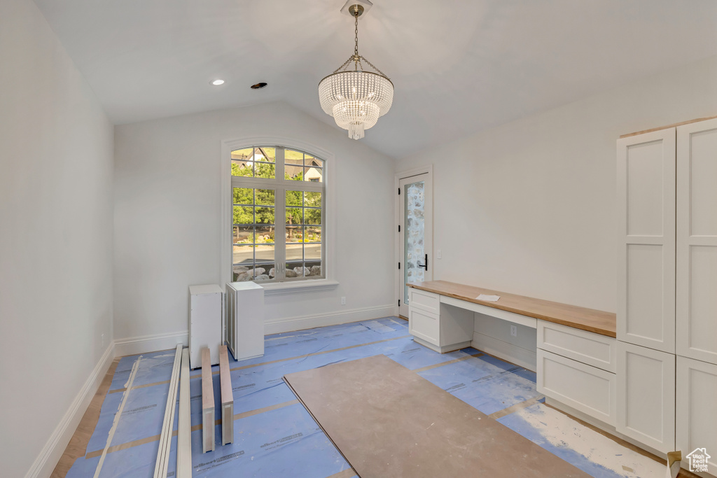 Unfurnished office with baseboards, a chandelier, lofted ceiling, and built in desk
