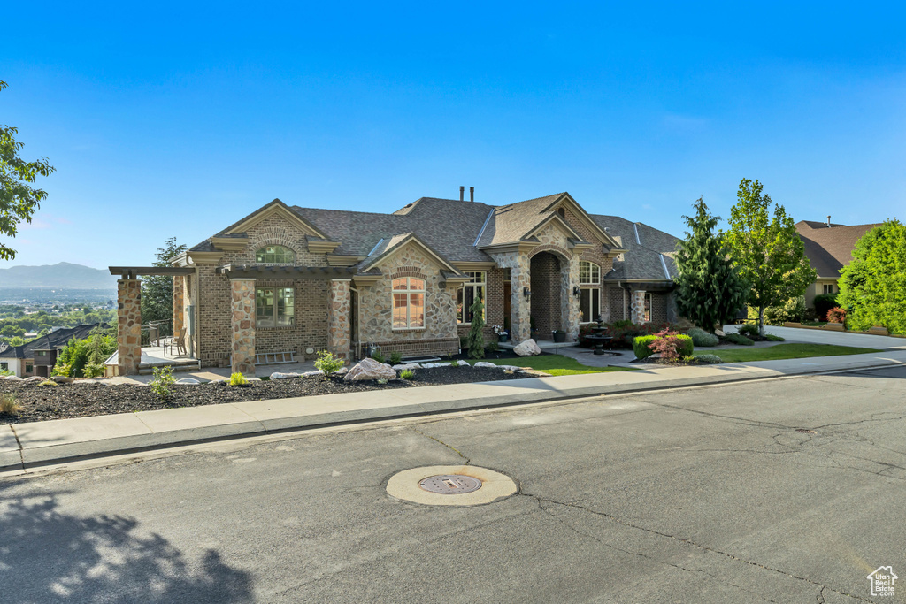 French country style house with brick siding, stone siding, and a shingled roof