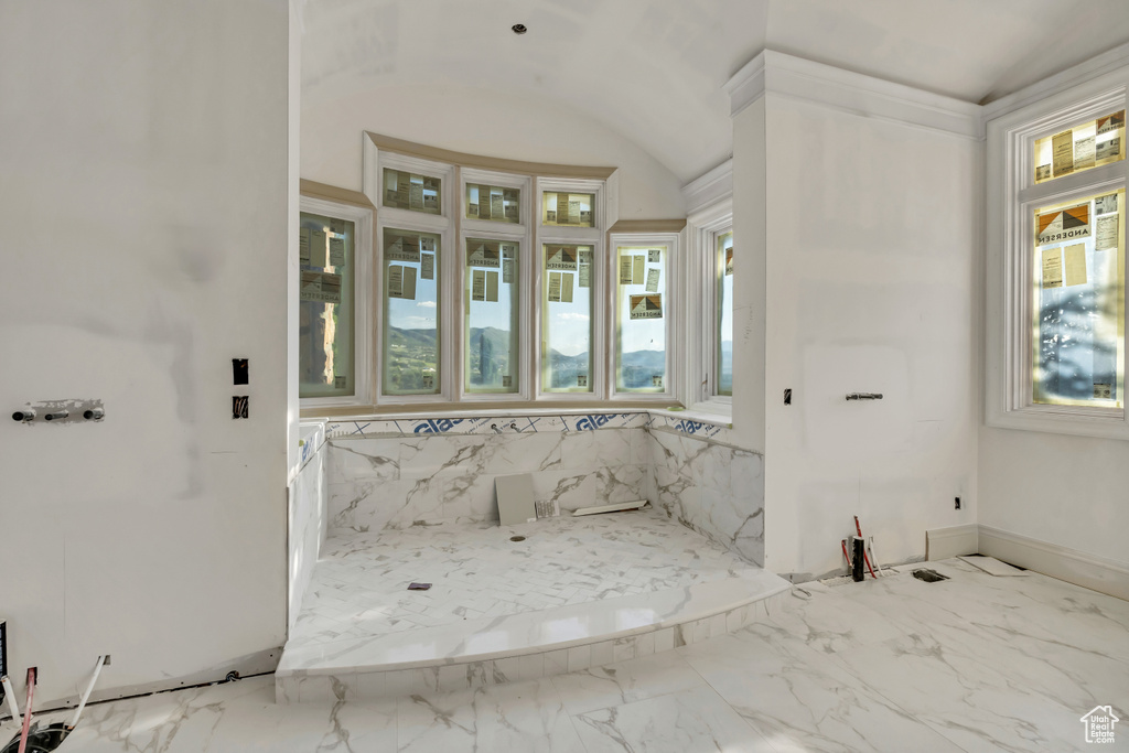 Bathroom featuring healthy amount of natural light, marble finish flooring, vaulted ceiling, and baseboards