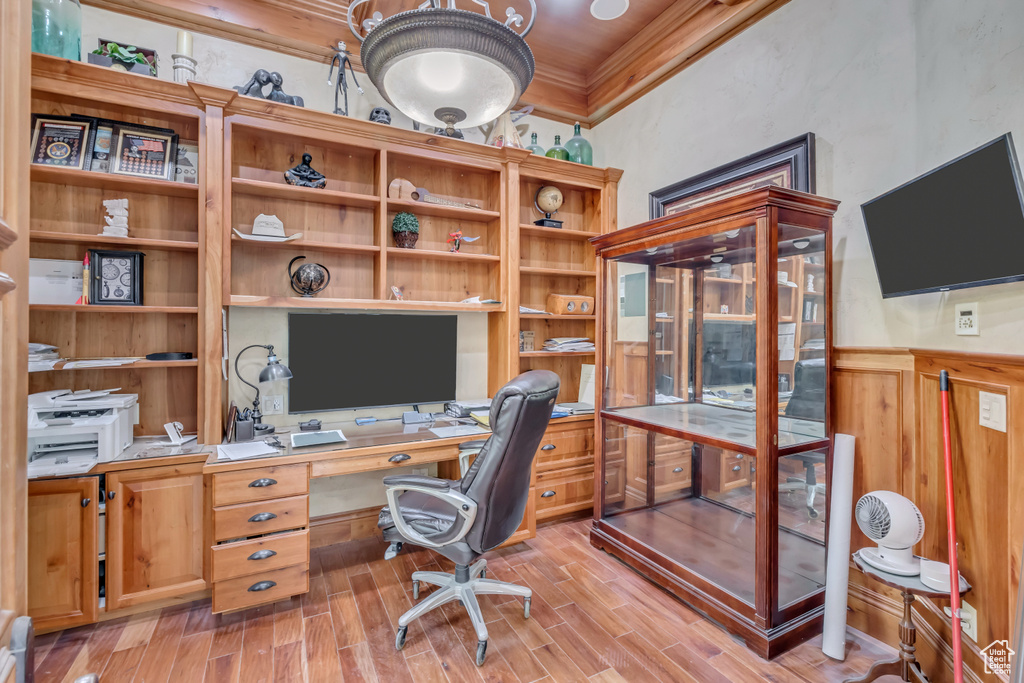 Office space with light wood finished floors, built in study area, and ornamental molding
