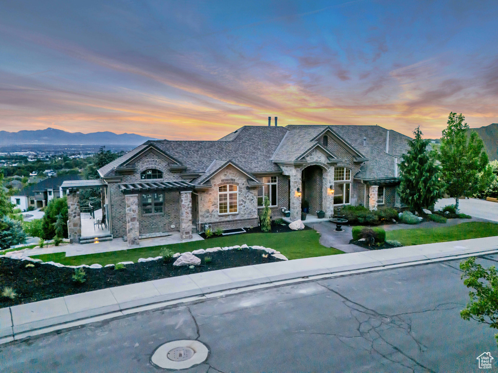 French country style house with stone siding, a standing seam roof, a yard, a mountain view, and a pergola