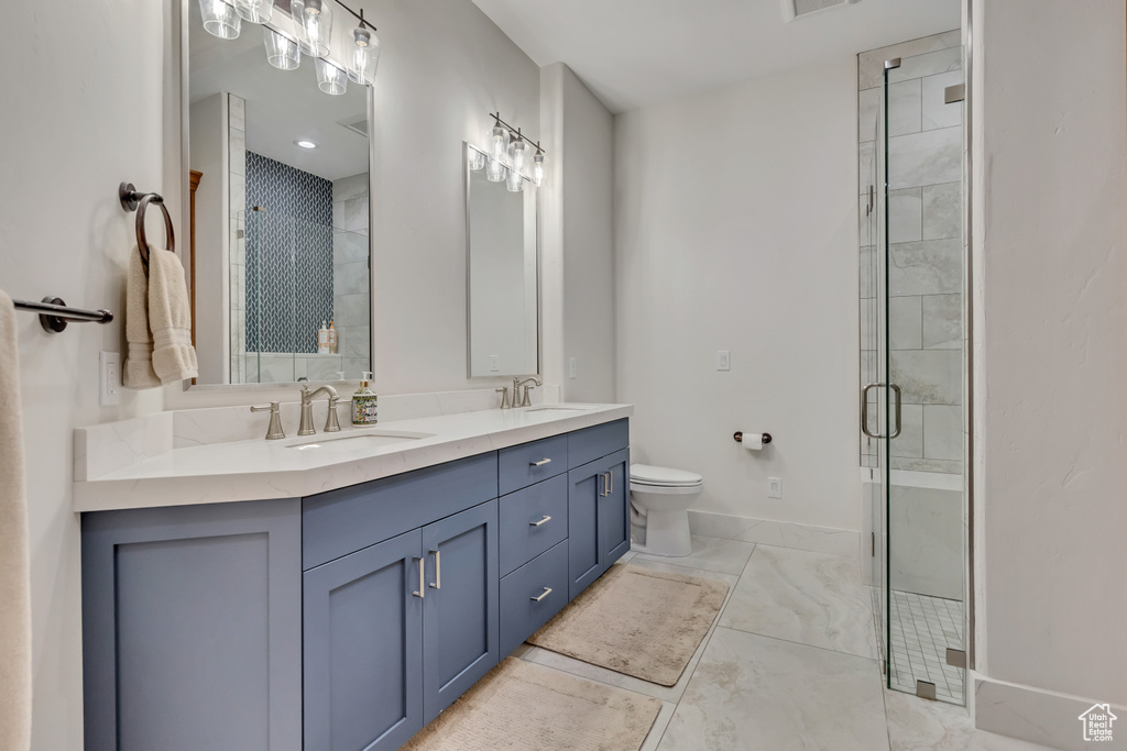 Full bathroom with double vanity, a stall shower, toilet, baseboards, and marble look tile flooring