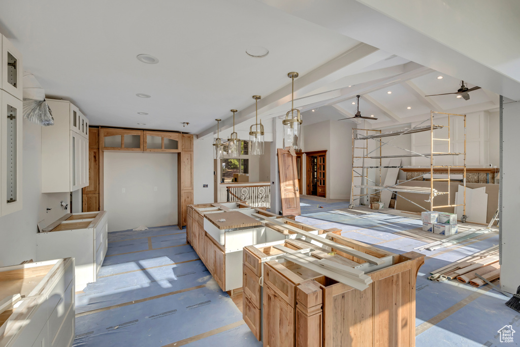 Kitchen with ceiling fan, glass insert cabinets, white cabinetry, decorative light fixtures, and a center island