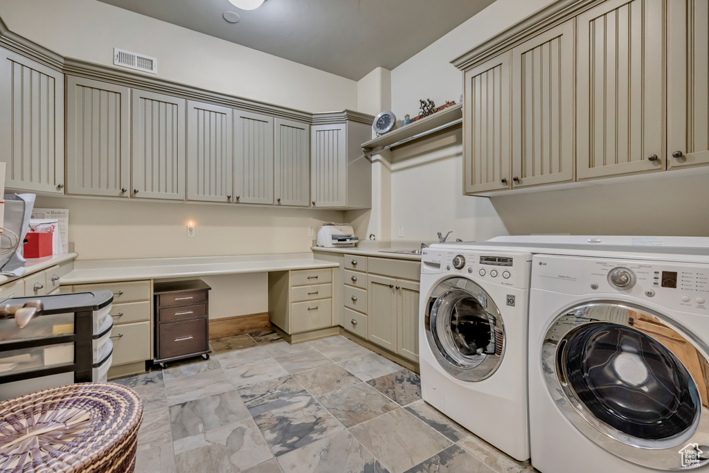 Laundry area featuring washer and dryer, cabinet space, baseboards, and light stone finish floors