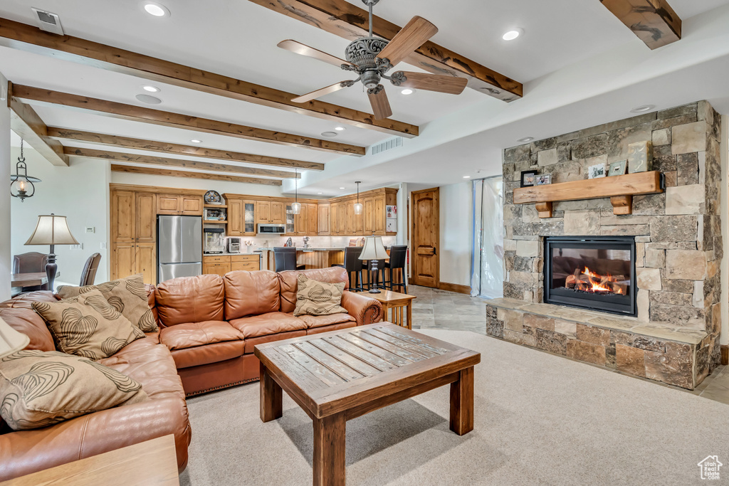Living area featuring a ceiling fan, recessed lighting, beam ceiling, and a stone fireplace