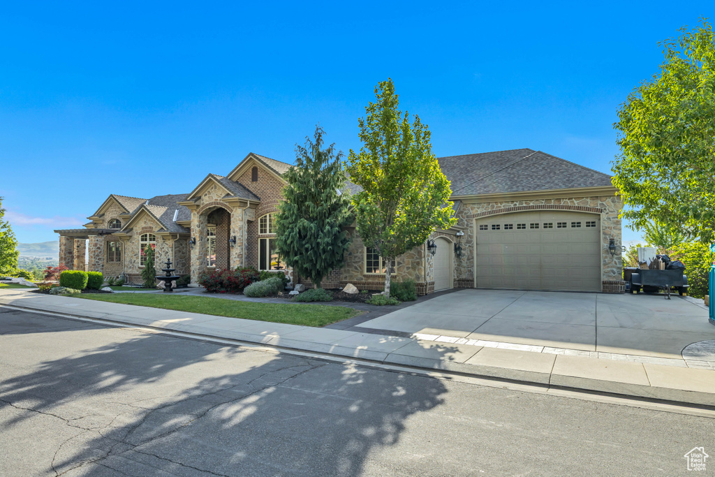 French country home featuring stone siding, concrete driveway, a garage, and a shingled roof