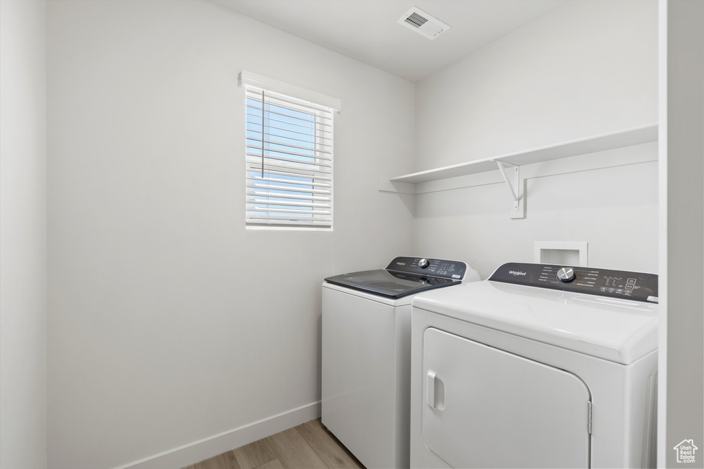 Laundry room with separate washer and dryer and light wood-type flooring