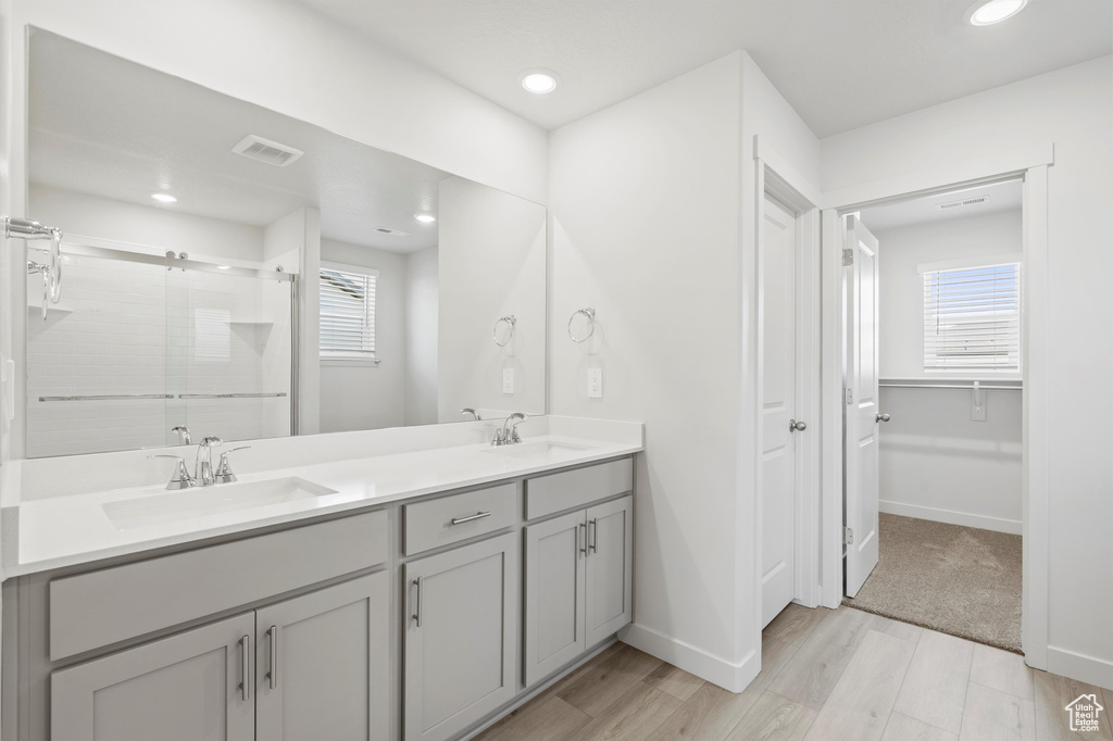 Bathroom featuring wood finished floors, double vanity, a stall shower, plenty of natural light, and recessed lighting