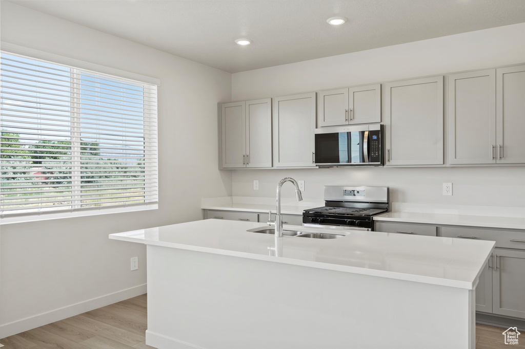 Kitchen featuring stainless steel microwave, gas stove, plenty of natural light, light wood-type flooring, and recessed lighting