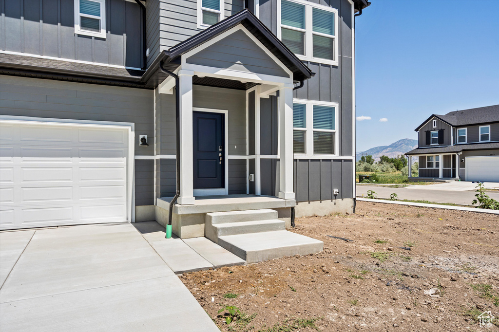 View of exterior entry featuring board and batten siding, a mountain view, driveway, and a garage