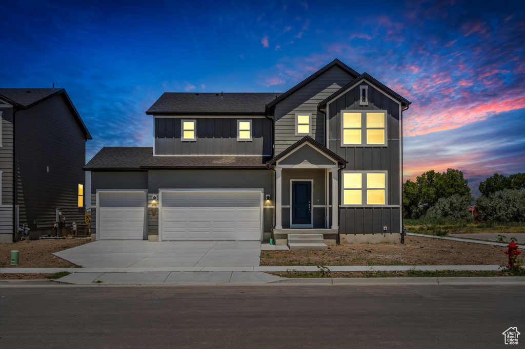 View of front of property featuring board and batten siding, concrete driveway, a garage, and roof with shingles