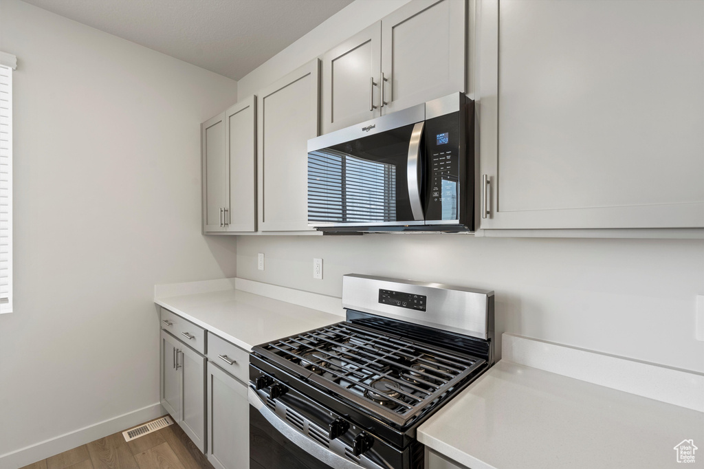 Kitchen with stainless steel appliances, light wood-style flooring, and light countertops