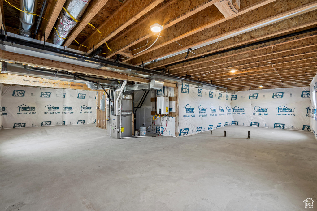 Unfinished below grade area featuring tankless water heater and heating unit