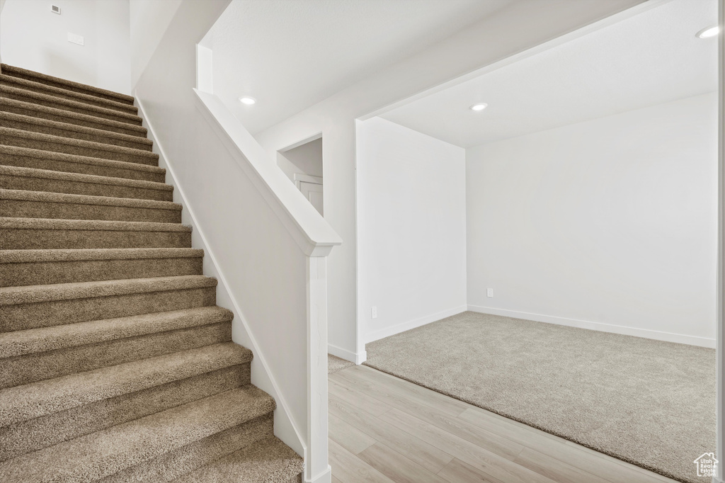 Staircase with wood finished floors and recessed lighting