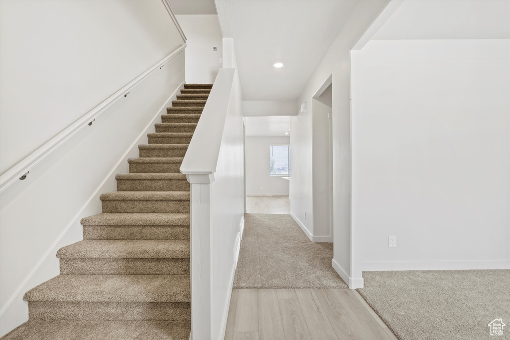 Staircase featuring wood finished floors and recessed lighting