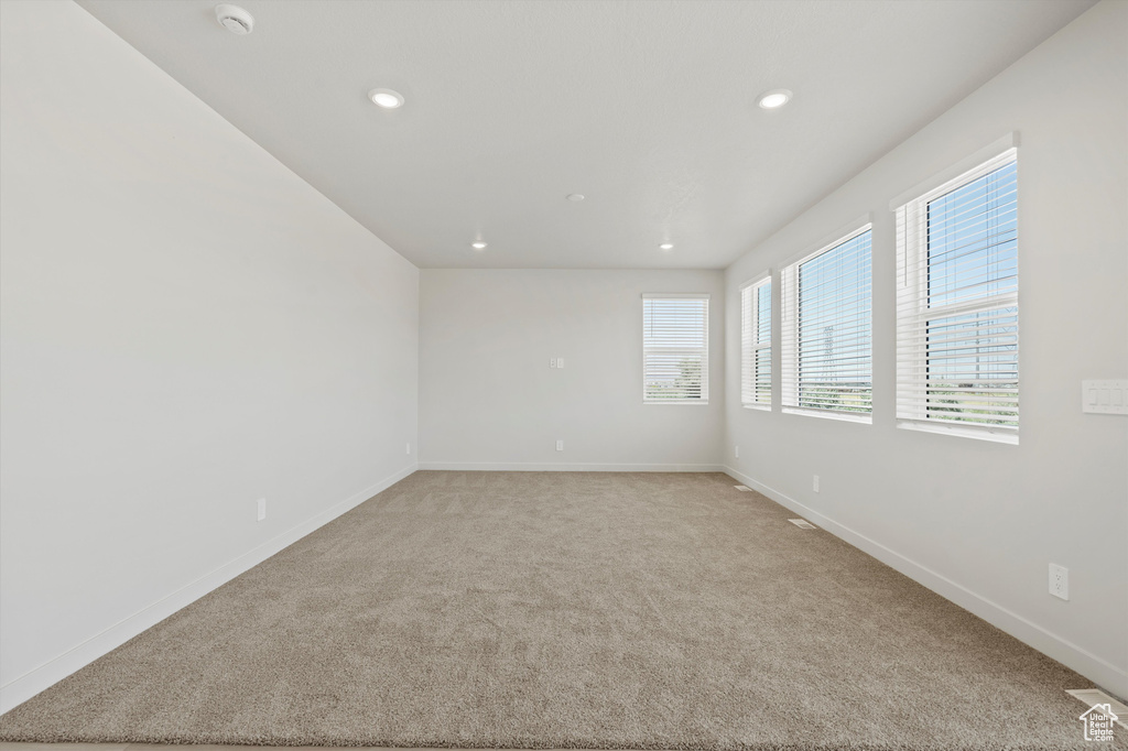 Unfurnished room featuring healthy amount of natural light, recessed lighting, a smoke detector, and light colored carpet