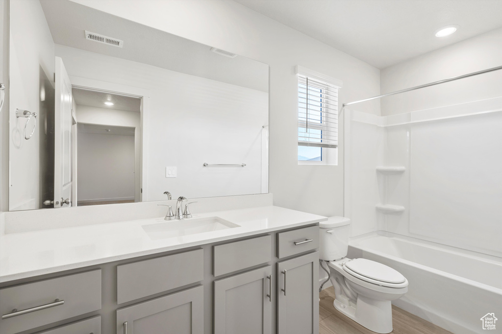 Bathroom with vanity, bathing tub / shower combination, wood finished floors, and recessed lighting