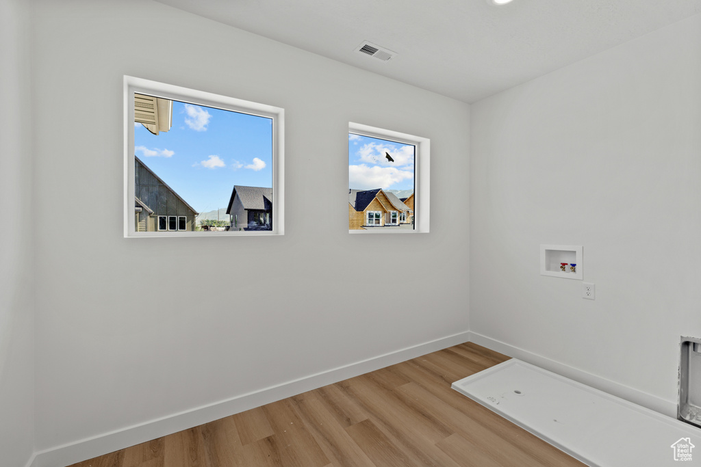 Washroom featuring light wood-type flooring, washer hookup, and baseboards