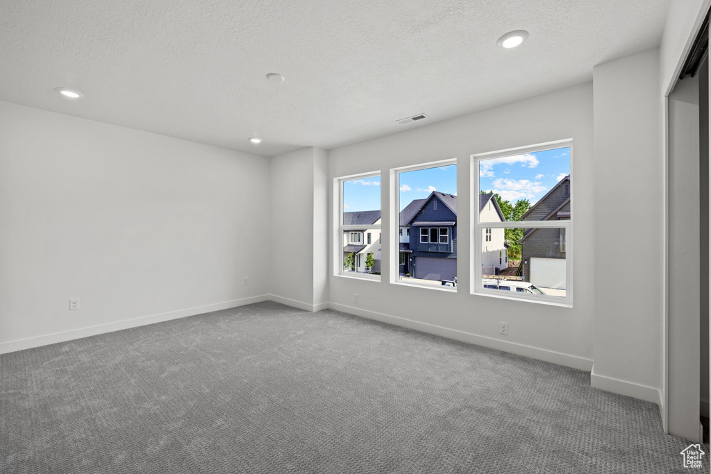 Empty room with recessed lighting, carpet floors, a textured ceiling, and baseboards