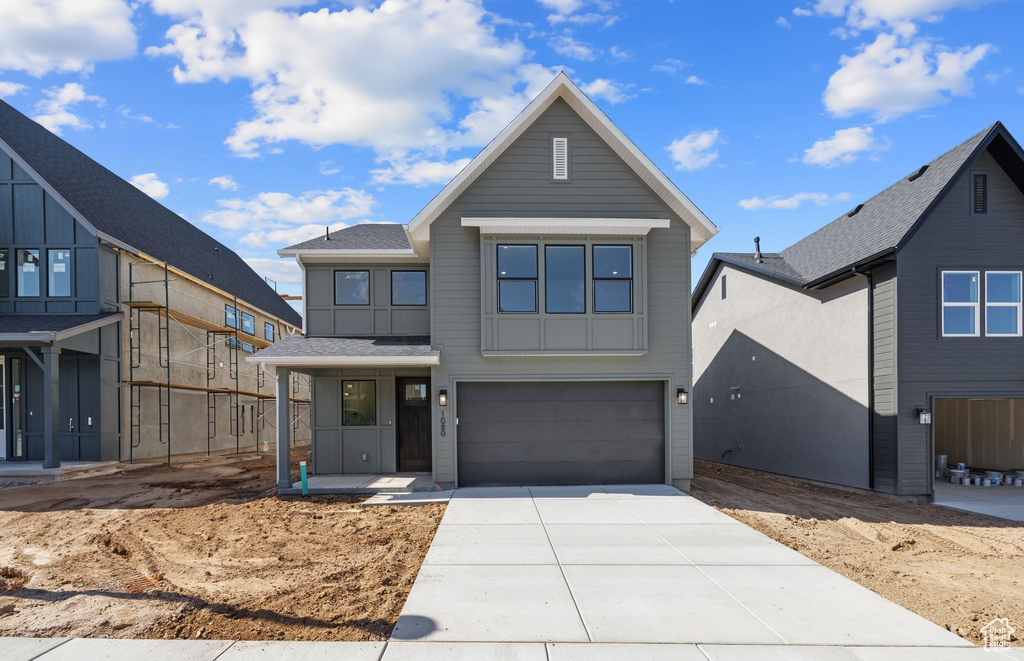 View of front facade with an attached garage, driveway, and a shingled roof