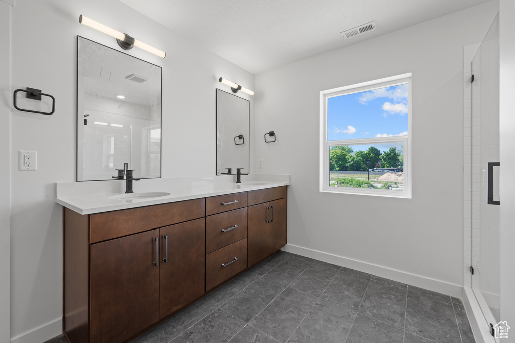 Bathroom featuring baseboards, double vanity, and a shower stall