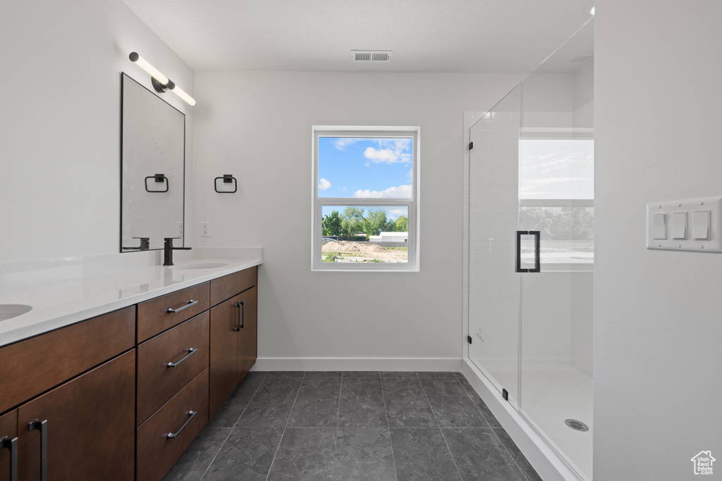 Bathroom with double vanity, a stall shower, and baseboards