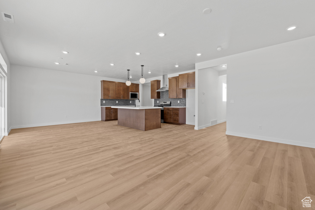 Kitchen with open floor plan, stainless steel appliances, light countertops, tasteful backsplash, and an island with sink