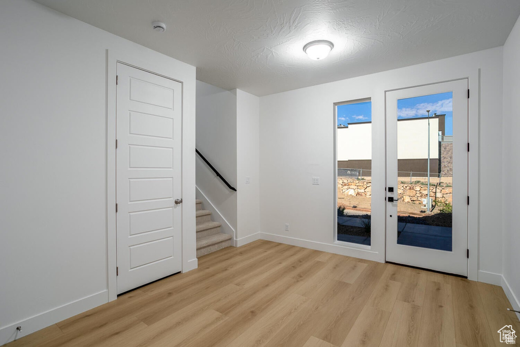 Spare room featuring light wood-style flooring, stairs, baseboards, and a smoke detector