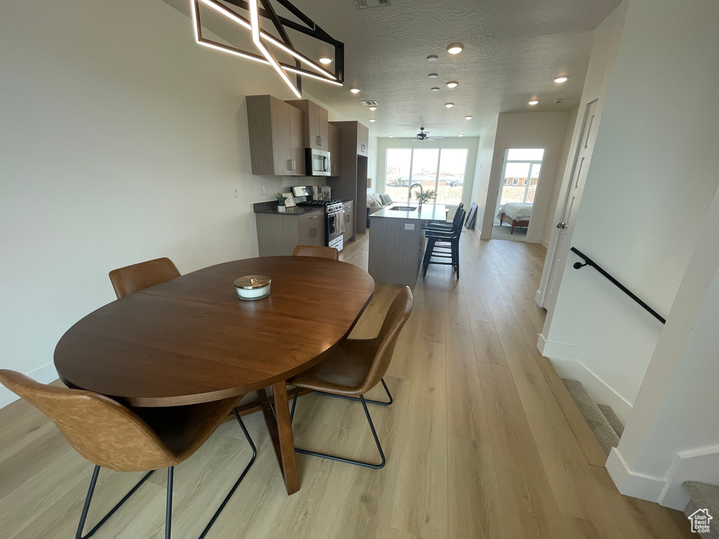 Dining area featuring light wood-style floors, recessed lighting, baseboards, and a textured ceiling