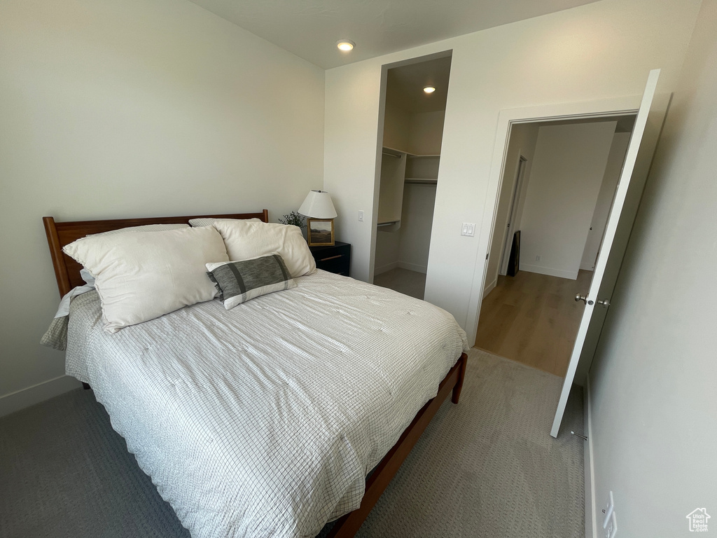 Bedroom with baseboards, a spacious closet, recessed lighting, a closet, and light carpet