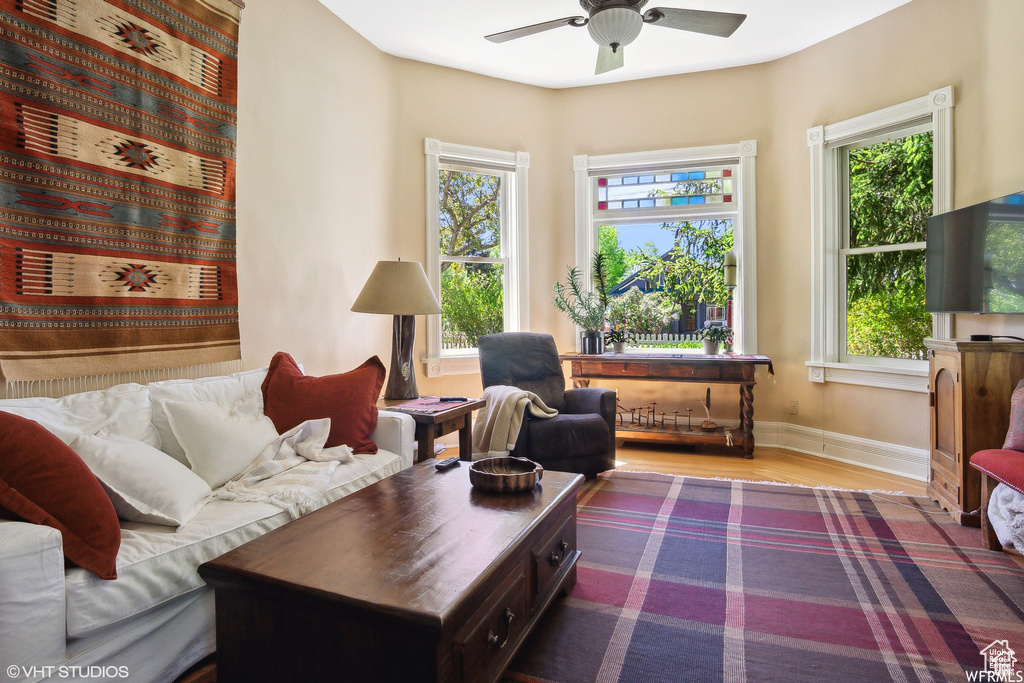 Living room featuring wood finished floors, healthy amount of natural light, baseboards, and ceiling fan