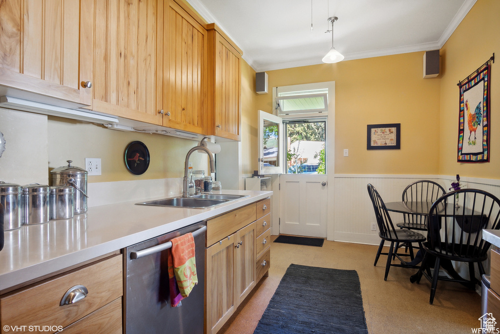 Kitchen with stainless steel dishwasher, a sink, light countertops, wainscoting, and ornamental molding