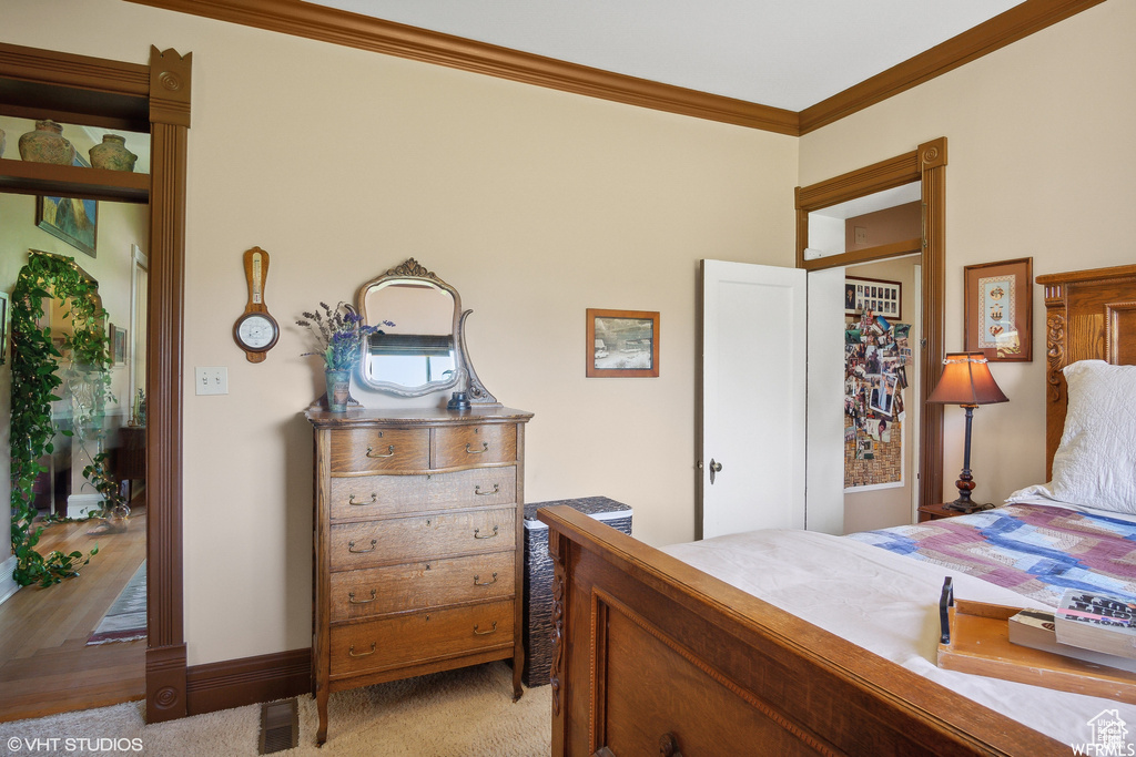 Bedroom with crown molding and light carpet