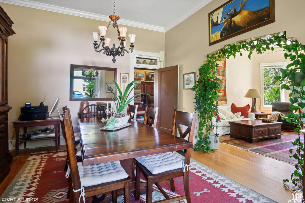 Dining area with wood finished floors, a chandelier, and crown molding