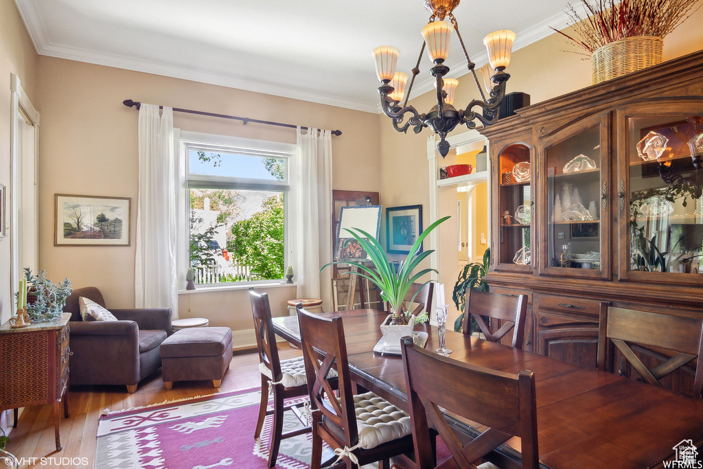 Dining space with a chandelier, wood finished floors, and crown molding