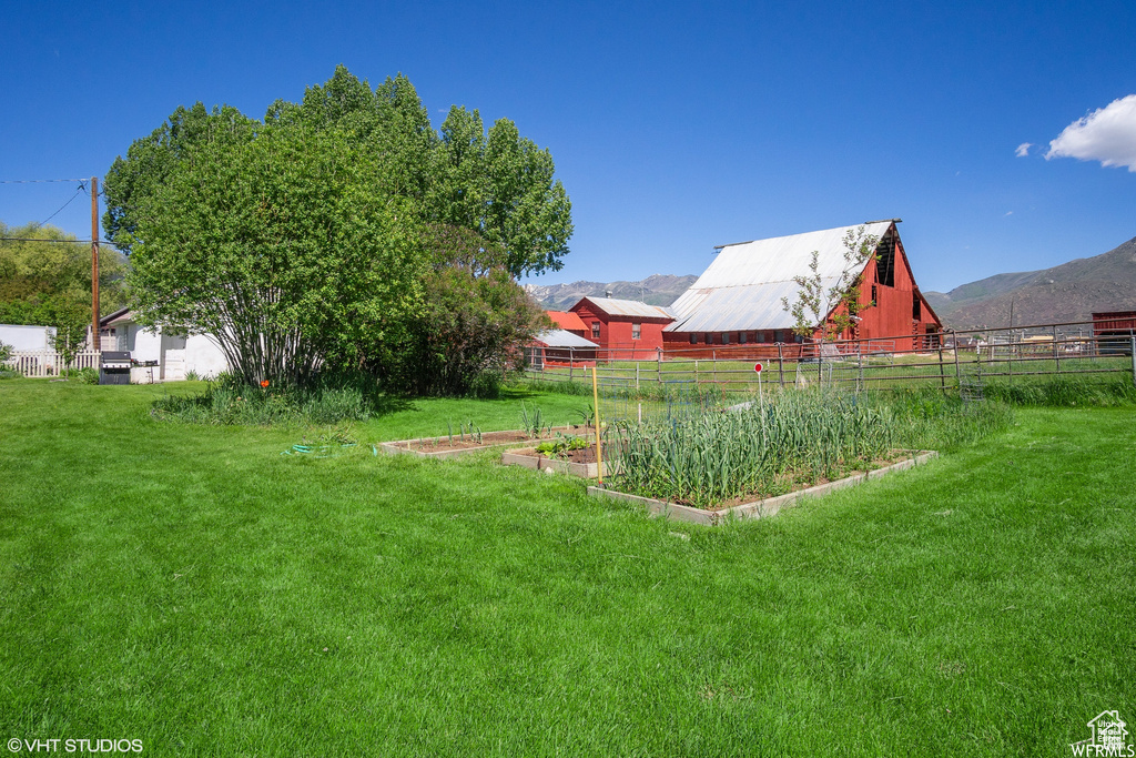 View of yard featuring a vegetable garden, a barn, a mountain view, and an outdoor structure