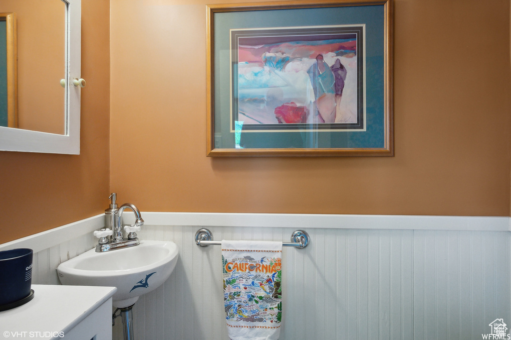 Half bath with a wainscoted wall and a sink