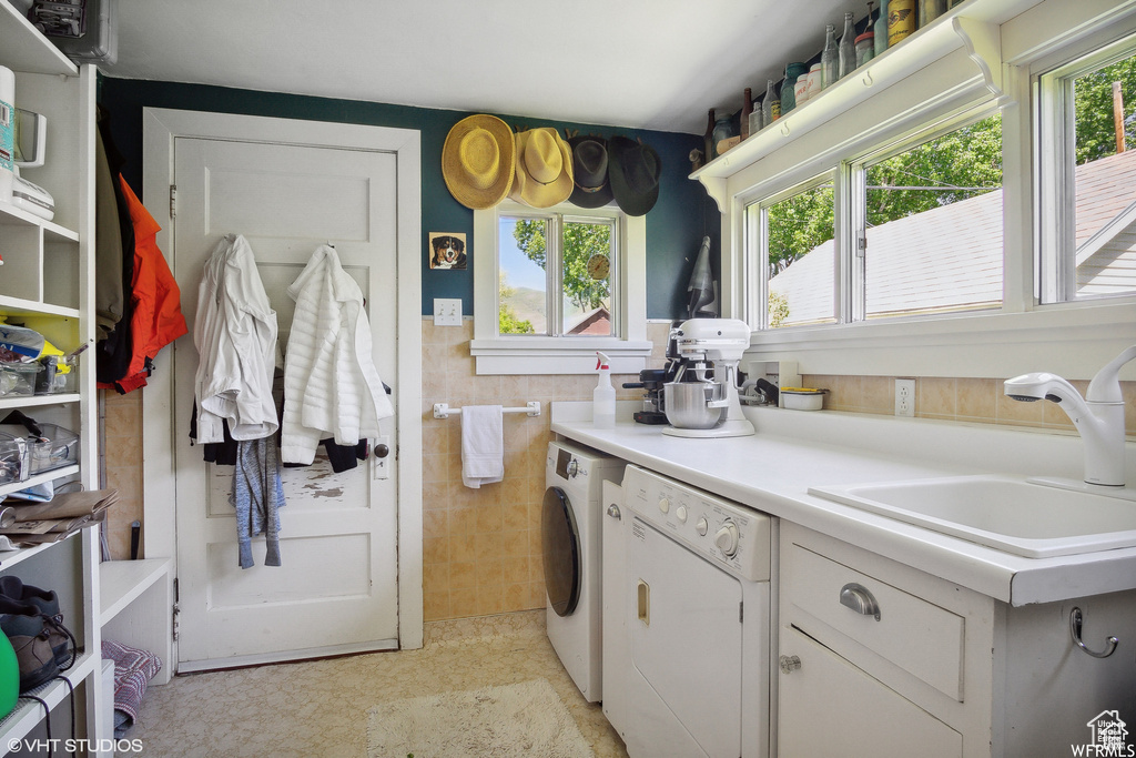 Kitchen with a sink, separate washer and dryer, white cabinets, light countertops, and dishwasher