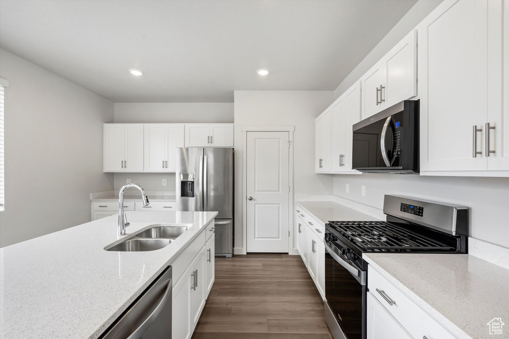 Kitchen with stainless steel appliances, light stone counters, dark wood-style flooring, white cabinetry, and recessed lighting