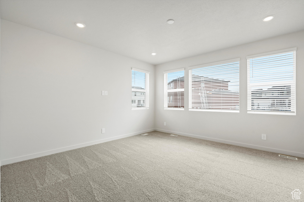 Empty room with light carpet and recessed lighting