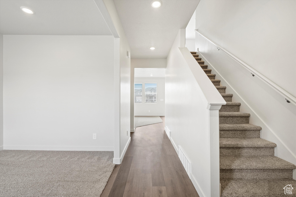 Stairway with recessed lighting and wood finished floors