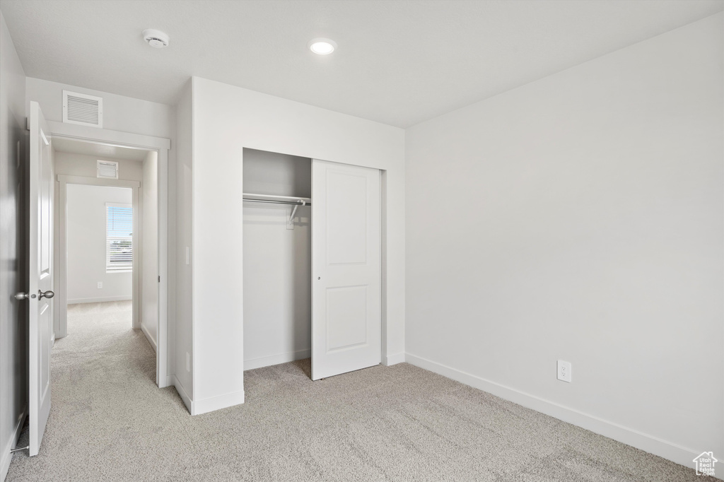 Unfurnished bedroom with light carpet, a closet, and recessed lighting